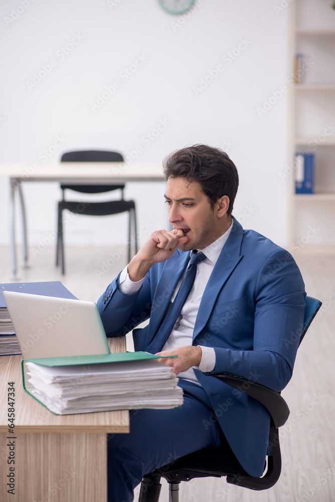 Young male employee and too much work in the office Young male employee and too much work in the office