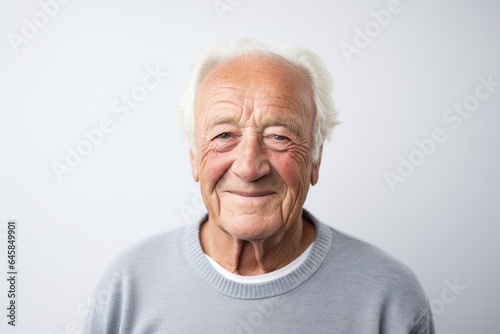 Portrait photography of a French man in his 80s wearing a simple tunic against a white background © Anne Schaum