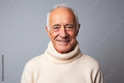 Medium shot portrait photography of a French man in his 80s wearing a cozy sweater against a minimalist or empty room background © Anne Schaum
