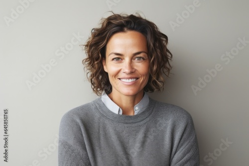Portrait photography of a Italian woman in her 40s wearing a cozy sweater against a minimalist or empty room background © Anne Schaum