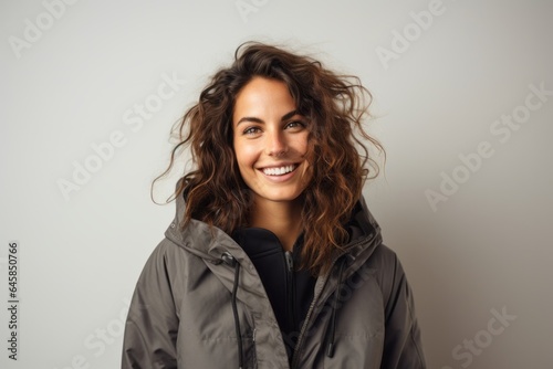 Portrait photography of a Italian woman in her 30s wearing a warm parka against a minimalist or empty room background