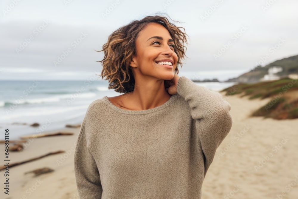 Lifestyle portrait photography of a Colombian woman in her 30s wearing a cozy sweater against a beach background Lifestyle portrait photography of a Colombian woman in her 30s wearing a cozy sweater against a beach background
