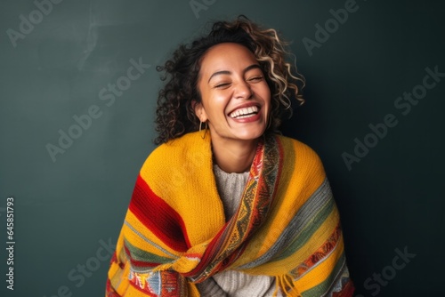 Medium shot portrait photography of a cheerful Peruvian woman in her 30s wearing a cozy sweater against an abstract background © Anne Schaum