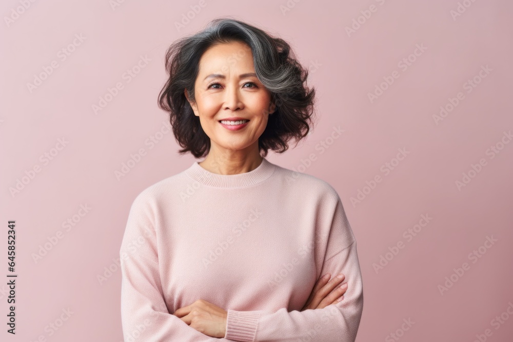 Medium shot portrait photography of a Vietnamese woman in her 50s wearing a cozy sweater against a pastel or soft colors background Medium shot portrait photography of a Vietnamese woman in her 50s wearing a cozy sweater against a pastel or soft colors background