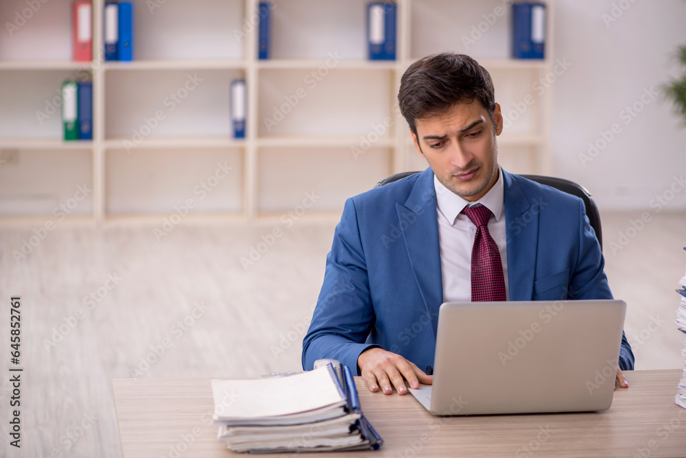 Young male employee and too much work in the office Young male employee and too much work in the office