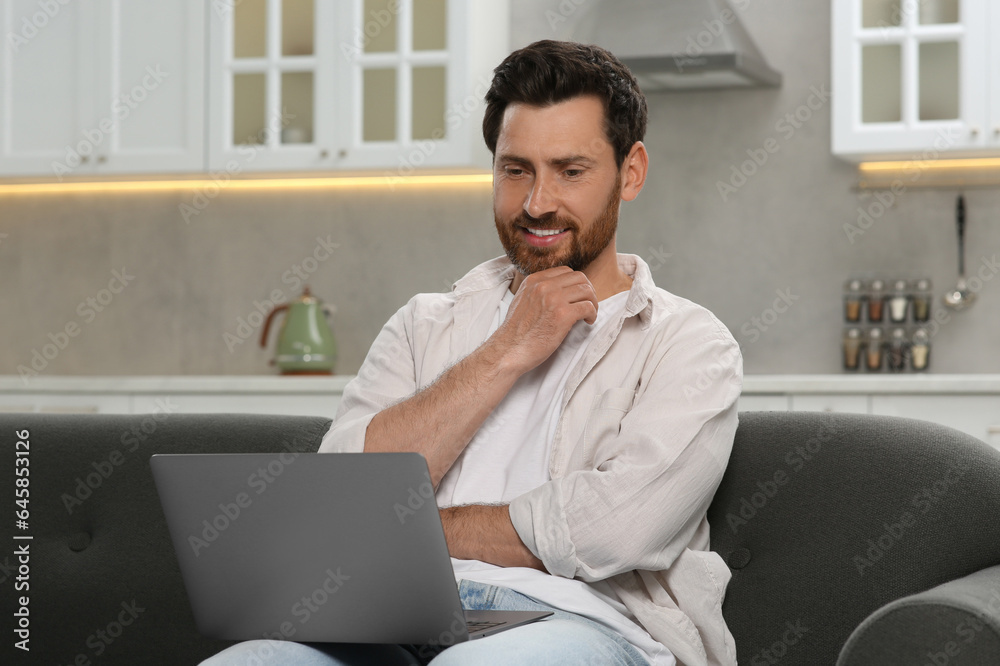 Man using laptop on couch at home