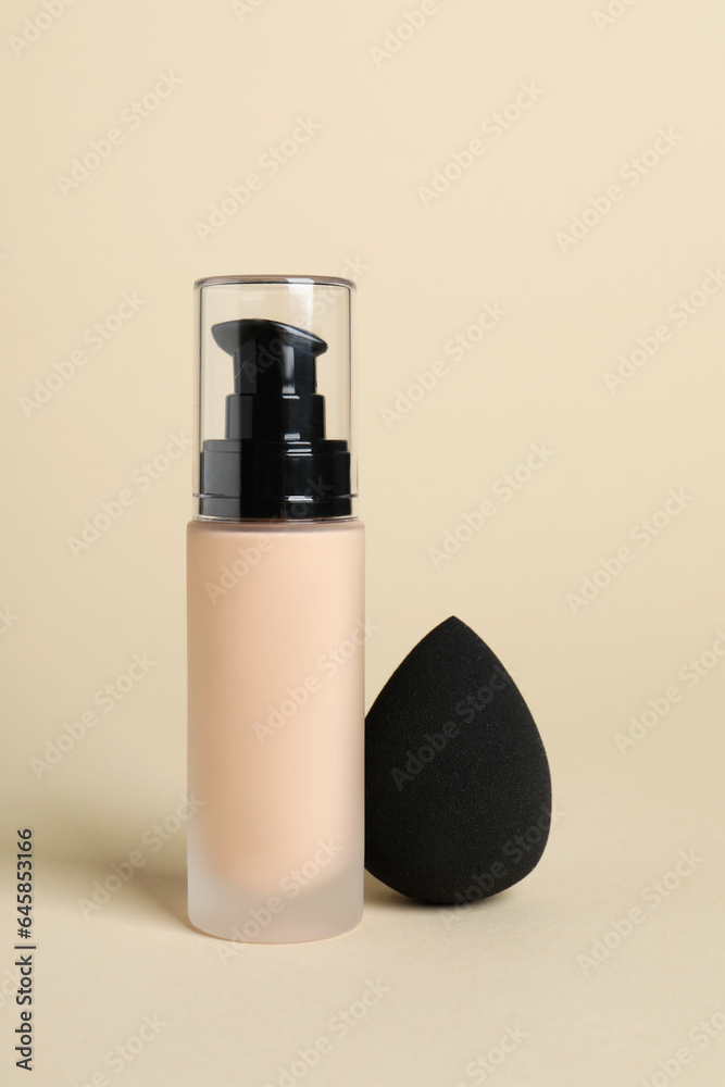 Bottle of skin foundation and sponge on beige background. Makeup product Bottle of skin foundation and sponge on beige background. Makeup product