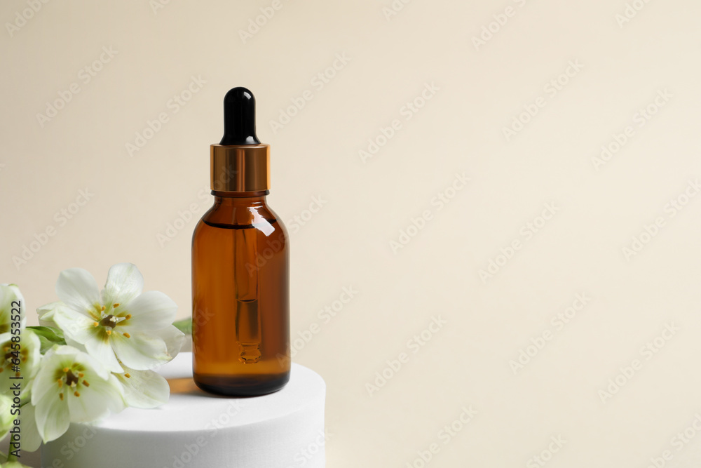 Bottle of cosmetic oil and flowers on beige background. Space for text Bottle of cosmetic oil and flowers on beige background. Space for text