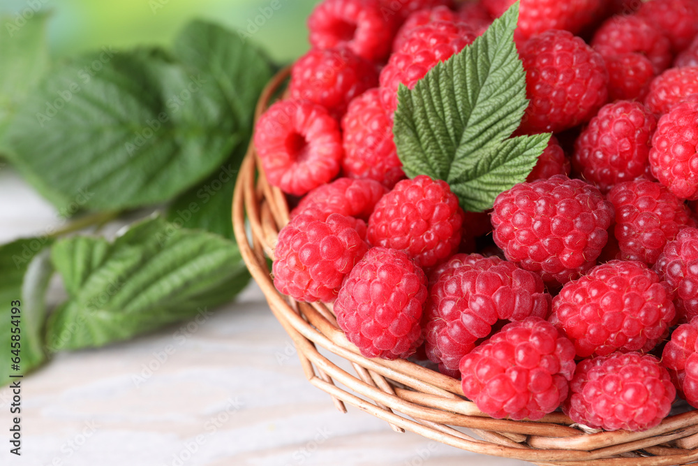 Tasty ripe raspberries and green leaves on light table, closeup Tasty ripe raspberries and green leaves on light table, closeup