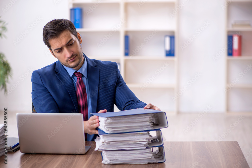 Young male employee and too much work in the office Young male employee and too much work in the office