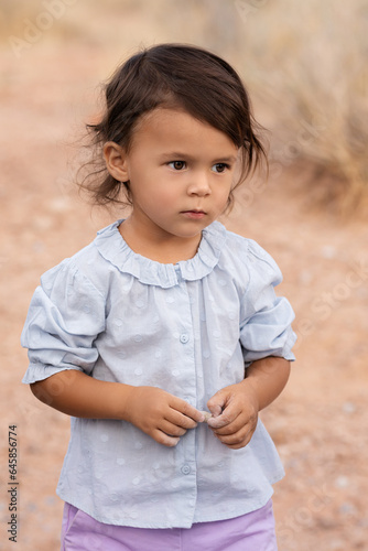 Little todder girl standing in desert, kids portrait and childhood memories concept photo