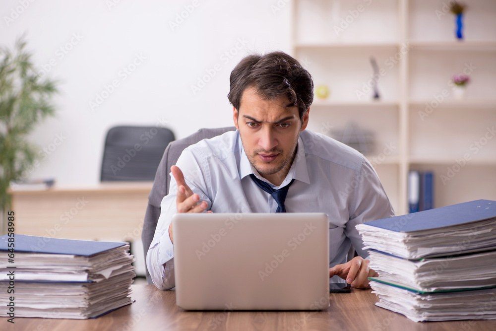 Young male employee and too much work in the office Young male employee and too much work in the office