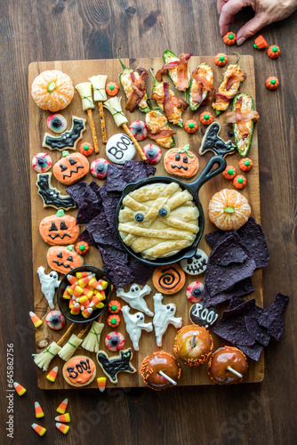 A hand decorating a Halloween themed charcuterie board with spooky treats.