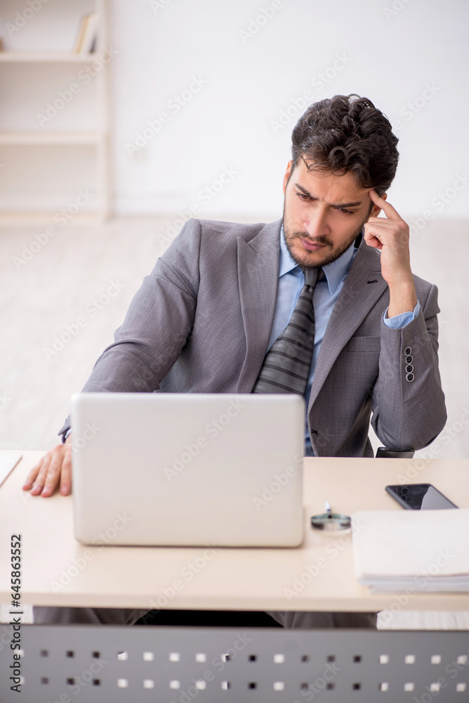 Young male employee and too much work in the office Young male employee and too much work in the office