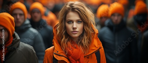 Concept of a woman standing out among a vast gathering of people and looking at the camera,.