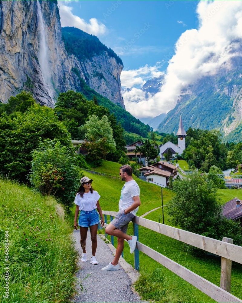 men and women visiting Lauterbrunnen valley with a gorgeous waterfall and Swiss Alps in the background, Berner Oberland, Switzerland, Europe during summer