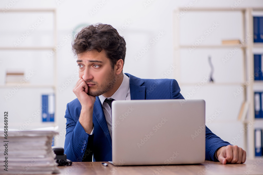 Young male employee and too much work in the office Young male employee and too much work in the office