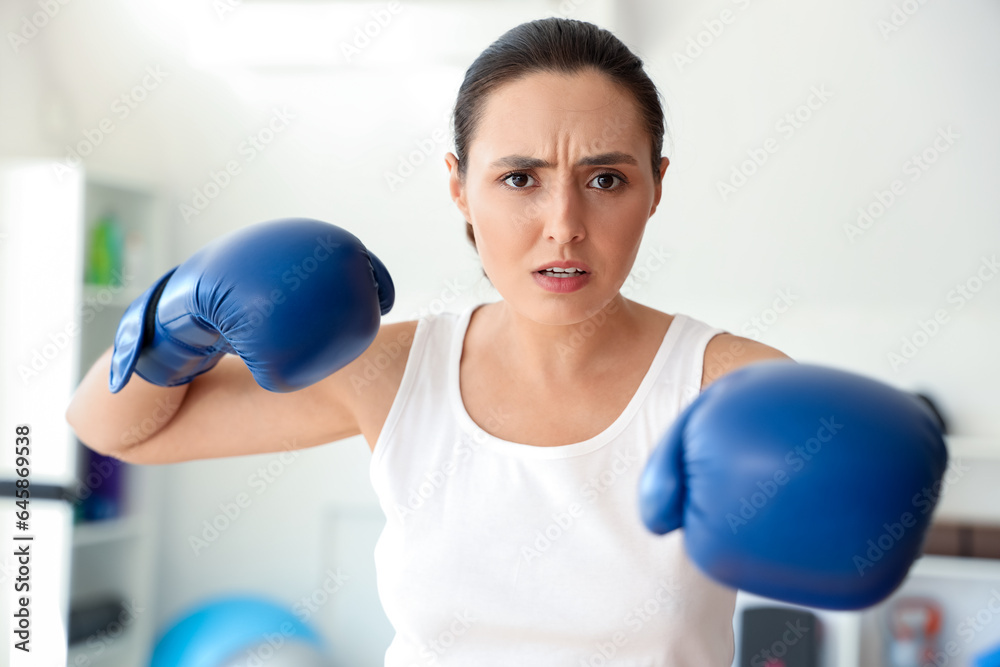 Young woman in boxing gloves training in gym. Concept of self defense Young woman in boxing gloves training in gym. Concept of self defense