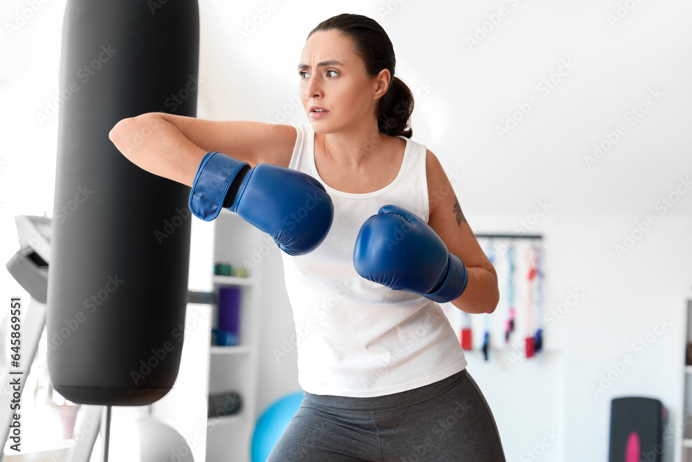 Young woman in boxing gloves training in gym. Concept of self defense
