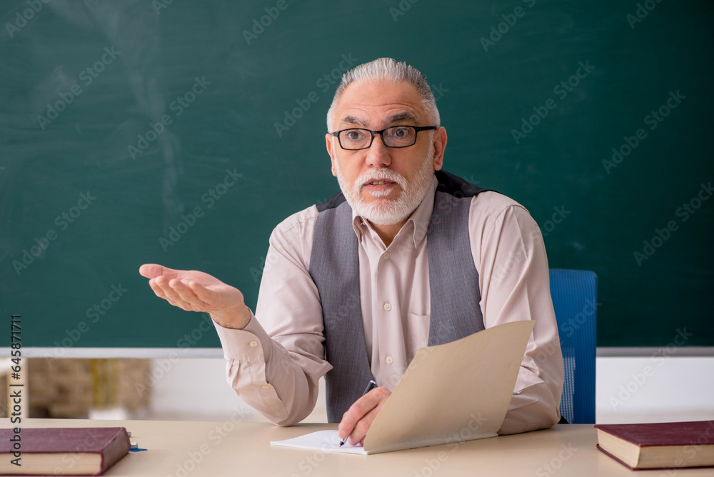 Old male teacher in the classroom Old male teacher in the classroom