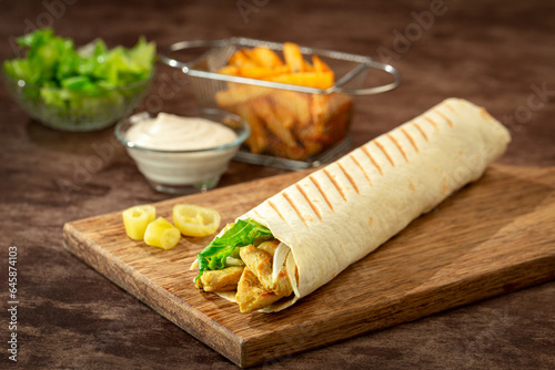 Tortilla wrap with chicken breast, vegetables and lettuce with curry mixture