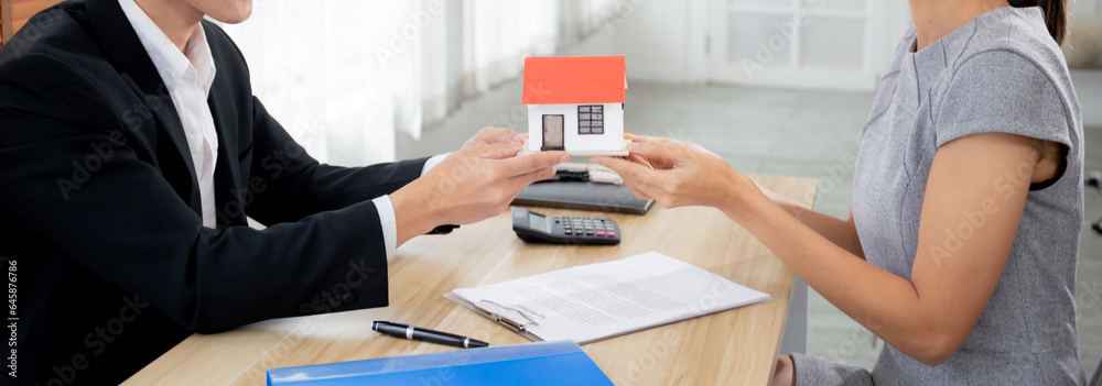 Young realtor man real estate giving house model to hands customer while agreement and contract achievement and approval at home office, investment and mortgage, business and finance concept. Young realtor man real estate giving house model to hands customer while agreement and contract achievement and approval at home office, investment and mortgage, business and finance concept.