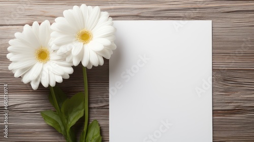 white flowers on a wooden background with blank white paper 