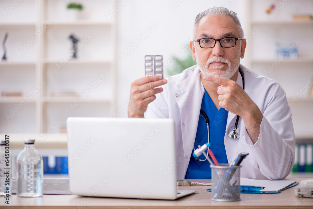 Fototapeta premium Old male doctor working in the clinic