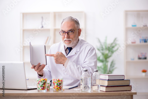 Old male doctor holding book in the clinic