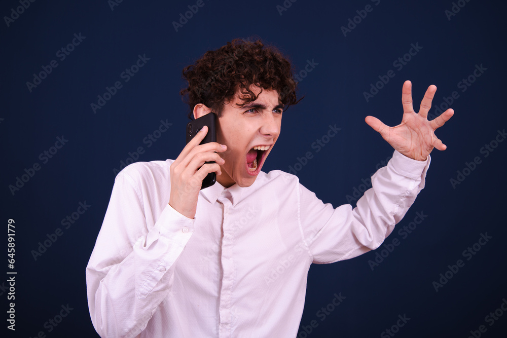 Funny curly guy talking on the phone and posing on a blue background. Funny curly guy talking on the phone and posing on a blue background.