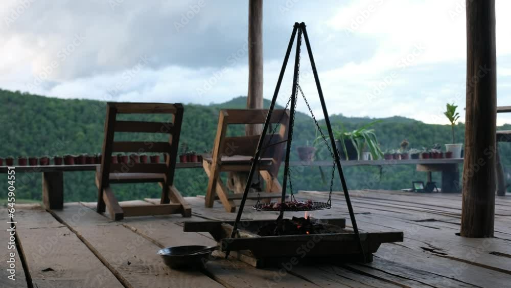 Pork grilled on hanging stove and chairs in wooden house terrace Pork grilled on hanging stove and chairs in wooden house terrace