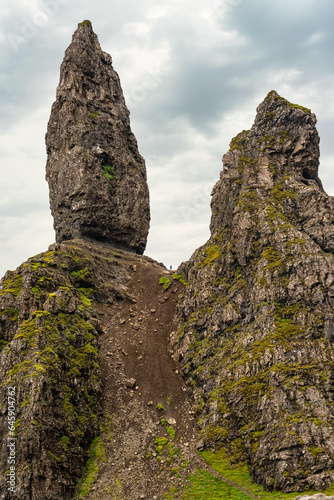 Strange rock formations in the so-called Old Man of Storr and small climber figure high up, Scotland.