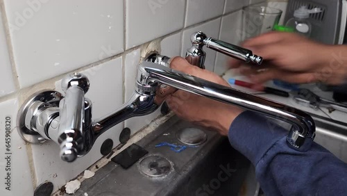 Plumber installing new faucet in kitchen sink photo