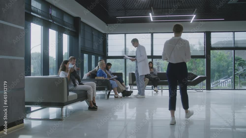 Diverse people sit on sofas in clinic lobby area, wait for appointment with doctor. Doctor speaks with elderly couple about medical test results. Waiting area in modern medical center. Healthcare. Diverse people sit on sofas in clinic lobby area, wait for appointment with doctor. Doctor speaks with elderly couple about medical test results. Waiting area in modern medical center. Healthcare.