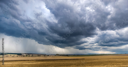 Starkregen und dunkler Wolken ziehen über Äcker und Felder