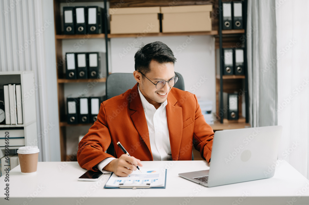 Asian business man typing laptop and tablet Placed at the table at the modern office.. Asian business man typing laptop and tablet Placed at the table at the modern office..