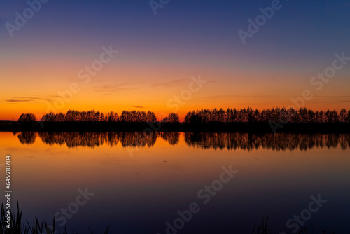 beautiful orange-yellow sunset on the lake in spring © rsooll
