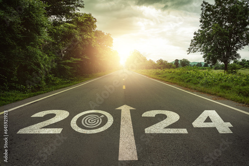 Goals, targets in New year 2024 or straightforward concept. Text 2024 and dartboard with dart icon on the road in the middle of asphalt road at sunset. Life, business planning, challenge, strategies.