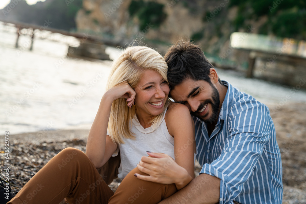 Romantic couple sitting at the beach. Attractive woman and handsome man spending the evening together and laughing while enjoying summer vacation. Romantic couple sitting at the beach. Attractive woman and handsome man spending the evening together and laughing while enjoying summer vacation.