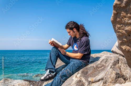 Giovane legge un libro antico in riva al mare
