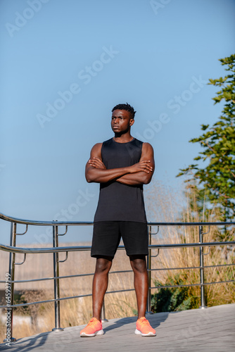 Full length of African athlete in sportswear keeping arms crossed while standing outdoors © gstockstudio