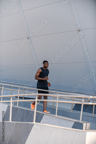 Full length of active African man in sportswear looking concentrated while running outdoors