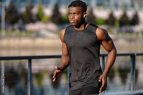 Active African man in sportswear looking concentrated while jogging outdoors