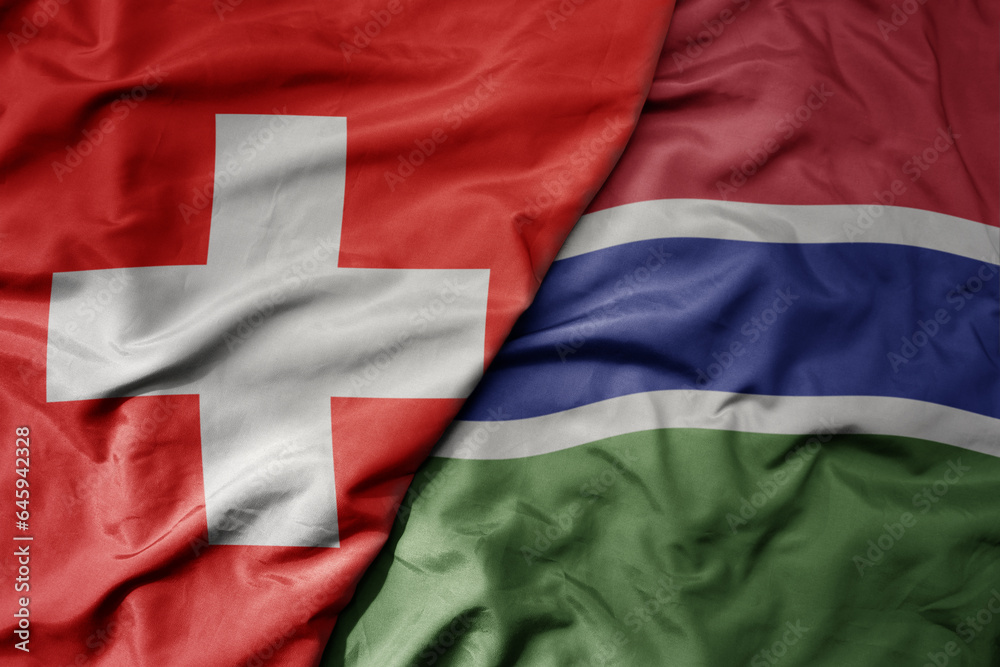 big waving national colorful flag of switzerland and national flag of gambia . big waving national colorful flag of switzerland and national flag of gambia .