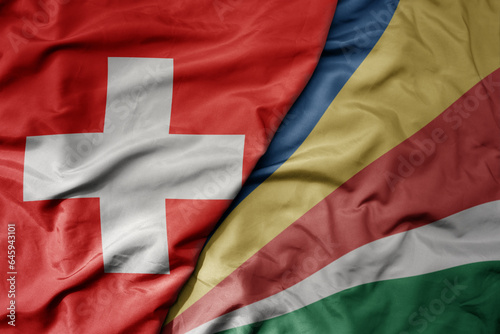 big waving national colorful flag of switzerland and national flag of seychelles .