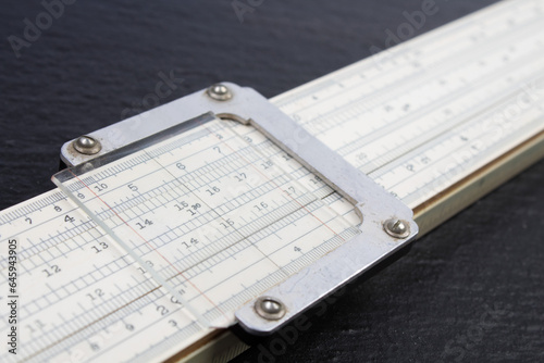 Logarithmic ruler on black background. Stationery for engineers and students.