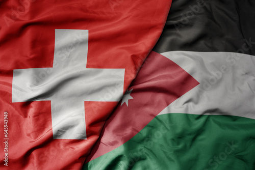 big waving national colorful flag of switzerland and national flag of jordan .