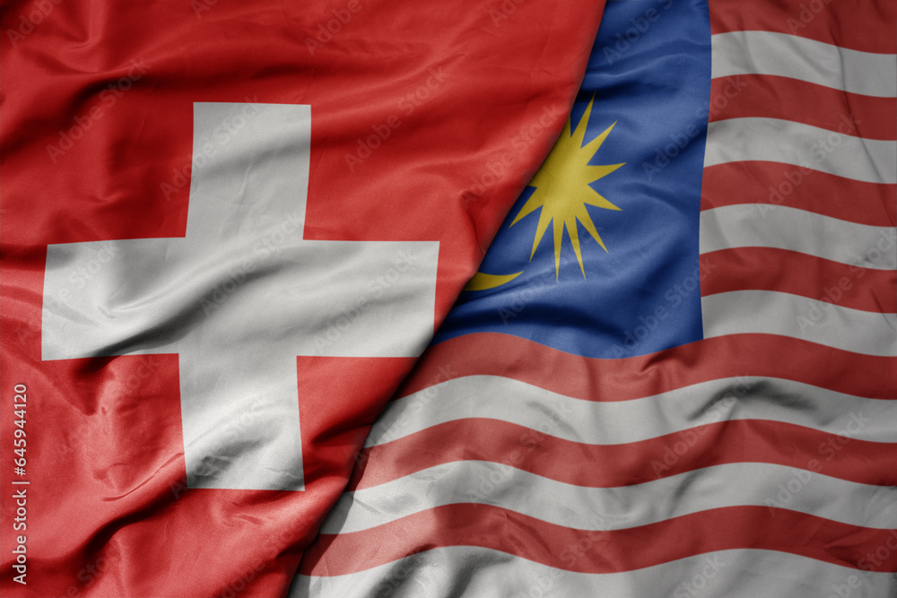 Fototapeta premium big waving national colorful flag of switzerland and national flag of malaysia .