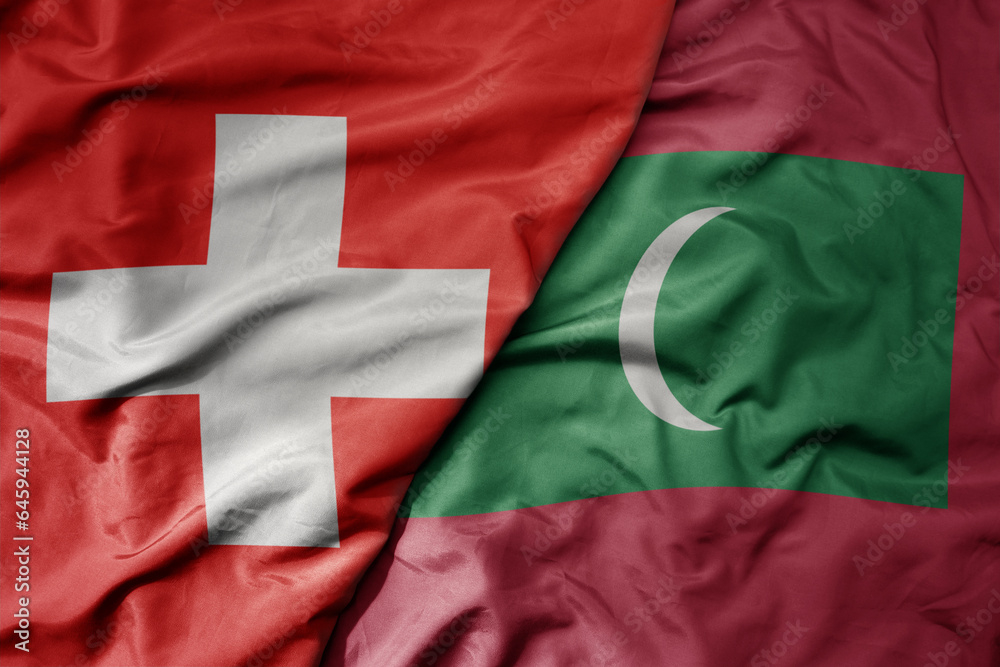 big waving national colorful flag of switzerland and national flag of maldives .