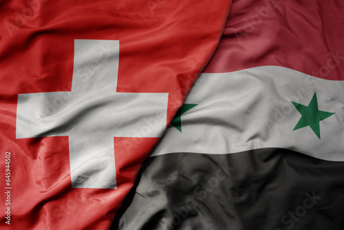 big waving national colorful flag of switzerland and national flag of syria .